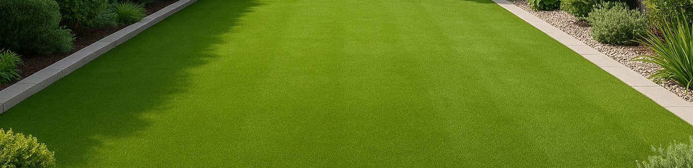 Gleichmäßig grüner Kunstrasen im Garten mit Pflasterstein-Einfassung und Beetumrandung