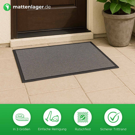 Schmutzfangmatte Tira in Anwendung vor dunkelbrauner Haustür auf hellem Steinboden